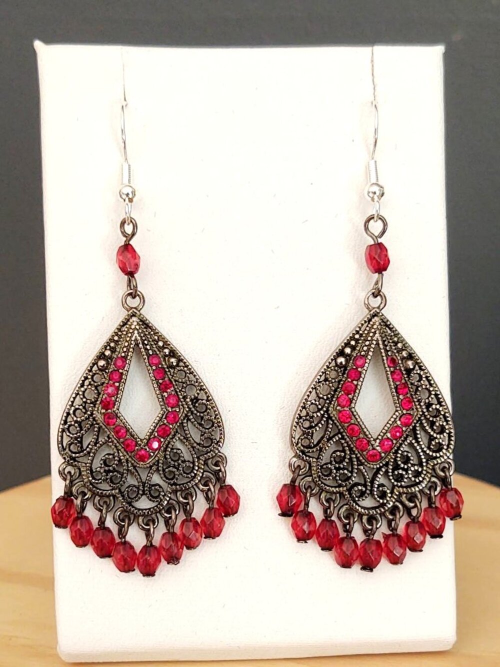 Dark silver tone metal dangle earrings with red crystal accent and beads
